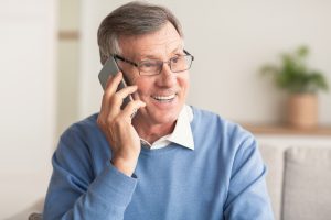 Phone Call. Happy Elderly Man Talking On Cellphone Sitting On Co