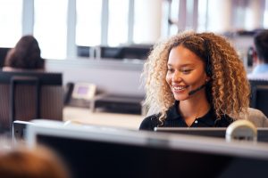 Young Businesswoman Wearing Telephone Headset Talking To Caller
